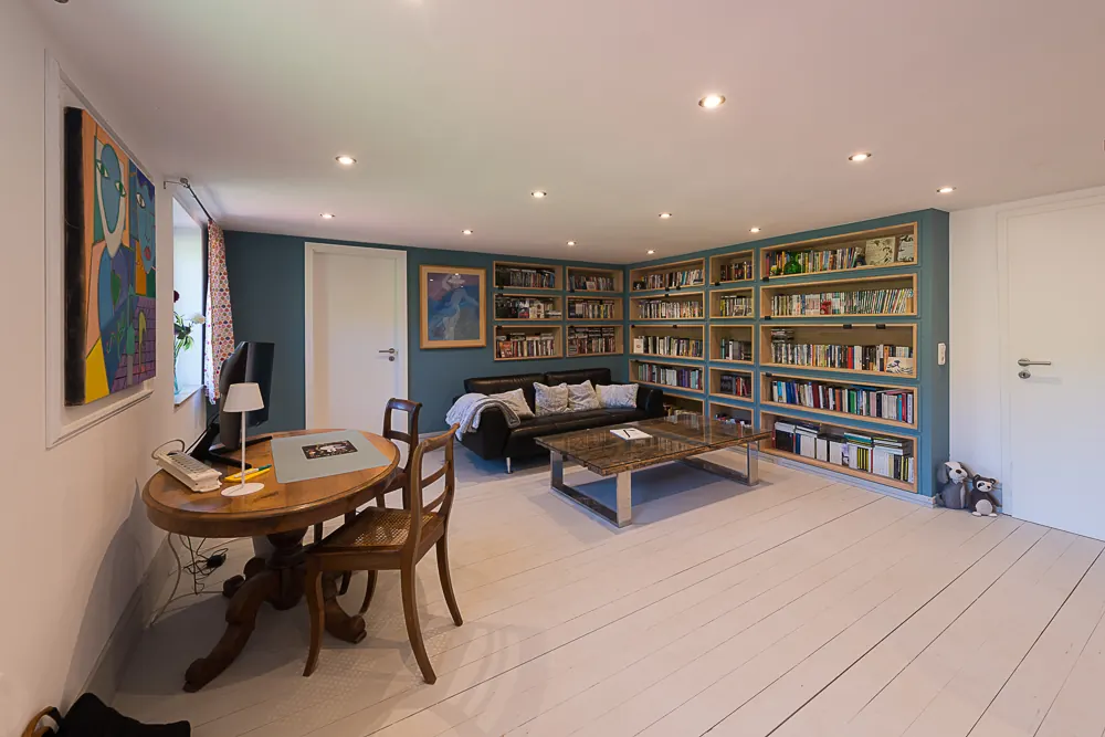 Großes Zimmer mit Bücherwand, Sofa und Mediathek